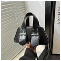 Detailed view of black punk bag with silver eyelets and wide industrial shoulder strap - Black