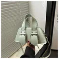 Detail der mintgrünen Punk-Handtasche mit Lederriemen und markanten Metallschnallen - Grün