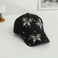Dettaglio degli strass a farfalla arcobaleno sulla visiera di un berretto da baseball nero - Nero