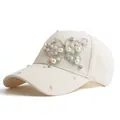Close-up of artificial pearls and rhinestones butterfly detail on cream baseball cap - Off White