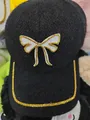 Detail of knitted baseball cap featuring rhinestone bow ornament and studded brim edge - Bow Style / Black