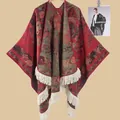Detail eines roten Strickponchos mit goldenen Blumenmustern und langen cremefarbenen Fransen - Floral Rot