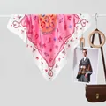 Detail van roze zijden sjaal met sterren- en hoefijzerpatronen op een leren tas - Strik