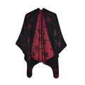 Close-up of jacquard poncho showing stars and dots pattern with fine edge stitching - One Size / Stars Black Red