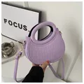 Close-up of purple PU leather handbag featuring vertical pleated texture and round handle - Purple