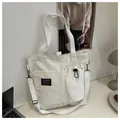 White canvas tote bag with adjustable strap and fashion instinct patch on front pockets - White