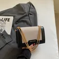 Sac à épaule chic en patchwork noir et beige avec chaîne dorée et étiquette mode - Noir