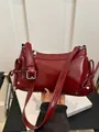 Elegante bolso de hombro en cuero brillante rojo oscuro con lazos y tachuelas plata - Burdeos