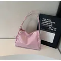 Pink glossy patent leather tote bag featuring side knot detail on white display stand - Pink