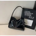 Macro detail of high-shine black leather tote bag with vintage pleated texture and side knot - Black