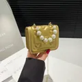 Gouden mini-crossbodytas met gewatteerd hartpatroon en decoratieve parelhandgreep - Goud