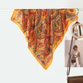 Fashionable paisley print silk scarf in vibrant orange yellow hung in a lifestyle setting - Yellow Paisley
