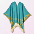 Detailed texture of blue knitted poncho featuring gold ethnic patterns and white tassels - Pullover Poncho Origin Blue