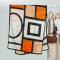 Détail d'une écharpe géométrique color-block suspendue à côté d'un manteau beige et sac - Style Long / Bloc de Couleur Géométrique Orange