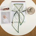 Detail van elegante zijden sjaal met kruisprint en donkergroene rand geknoopt in een strik - Groen Wit Mini Kruis (23)