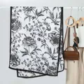 Elegant white velvet scarf with black floral print and thin black border hanging on rack - Black and White