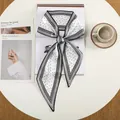 Detailopname van een zwart-witte zijden sjaal met geometrisch patroon gestrikt op een tafel - Zwart Wit Geometrische Streeprand (35)