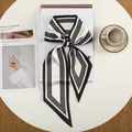 Detail van een zijden sjaal met zwart-witte stippen geknoopt op een tijdschrift en tafel - Zwart Wit Contrast Streep Polka Dot (29)