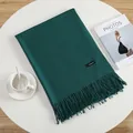 Close-up of dark green cashmere scarf with fringe details on a minimalist table - Verdant