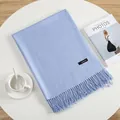 Elegant light blue cashmere scarf with tassels and stitched label on a white table - Sky Blue