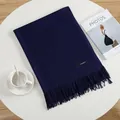 Detail shot of navy blue cashmere scarf with fringe on a white table with magazine - Navy Blue