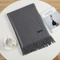 Detailed view of grey cashmere scarf with elegant tassels on a white minimalist desk - Dark Gray