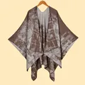 Dettaglio ravvicinato della trama geometrica a maglia e del morbido tessuto dello scialle poncho - caffè