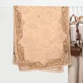 Detail van beige linnen sjaal met bruine paisley print hangend aan een witte hanger - Khaki