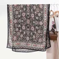 Dettaglio di una sciarpa floreale vintage appesa con borsa in pelle in scena moda - Nero