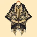Close-up of bohemian paisley patterns and fringe details on a knit shawl wrap - Black Camel