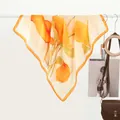 Detail of vibrant orange floral print silk scarf hanging with smooth glossy texture - 70x70cm / Golden Leaf