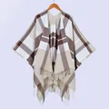 Close-up of soft plaid fabric texture and fine white tassel fringe on the shawl cape - Beige Plaid