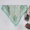 Detailansicht eines grünen Seidentuchs mit Paisleymuster neben einer Handtasche - 70x70 / Retro Vine Paisley Grün