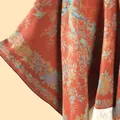 Detail eines Blumen-Strickschals mit rostrot Stoff und weißen Quastenfransen - Floral Orange