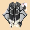 Detail eines geometrischen Strick-Ponchos mit Fransen und dickem Ethno-Farbmuster - Buchstabe OM Grau