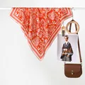 Exotic retro orange paisley square silk scarf styled with a leather bag on white background - Red