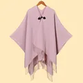 Details eines hellrosa Strickponchos mit schwarzer Lederschnalle und langen Fransenquasten - Rosa