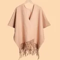 Close-up of beige thick wool shawl featuring fine knit texture and long fringe tassels - Pink