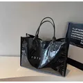 Glossy black mirror finish tote bag with white TOTE G print on a minimalist pedestal - Black