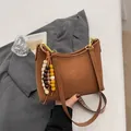 Braune Hobo-Tasche aus Leder mit Leopardenmuster-Gurt und dekorativem Holzperlen-Anhänger - Mit Anhänger / Braun