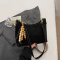 Schwarze Tragetasche mit weißen Kontrastnähten und Perlenquaste auf grauem Blazer - Mit Anhänger / Schwarz