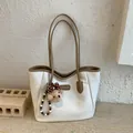 Dettaglio della borsa tote bianca con finiture in pelle marrone e ciondolo a forma di orso - Bianco Con Pendente