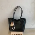 Dettaglio borsa tote in pelle nera con etichetta del marchio e ciondolo a orsetto - Nero Con Pendente