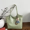 Sage green PU leather tote bag with cute bear charm on a wooden table setup - Green