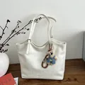 White faux leather tote bag with adjustable strap and a cute plush bear charm - White