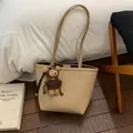 Detailed macro view of the beige lychee pattern tote bag with a cute teddy bear charm - Khaki With Pendant