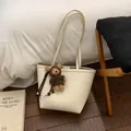 Détail d'un sac cabas blanc cassé à grain litchi avec un joli charm d'ours brun - Blanc Avec Pendentif