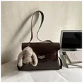 Donkerbruine leren schoudertas met pluche konijnenhanger en zilveren draaisluiting - Koffie Met Hanger