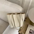 Minimalist creamy beige tote bag with litchi texture on a cozy neutral sofa - White Without Charm
