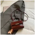 Detalle de un mini bolso bandolera burdeos en cuero brillante con cierre giratorio de metal - Rojo